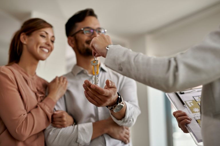 closeup-real-estate-agent-giving-couple-keys-their-new-home